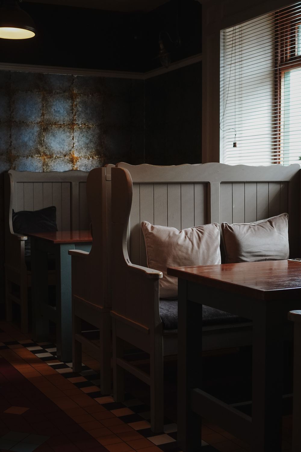 Cosy restaurant snug with painted settle benches and a tiled floor at The Tailor's House