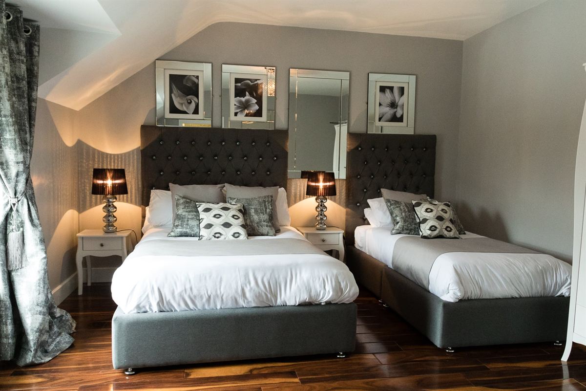 Twin guest room with a double and single bed, twin bedside lamps and bright window