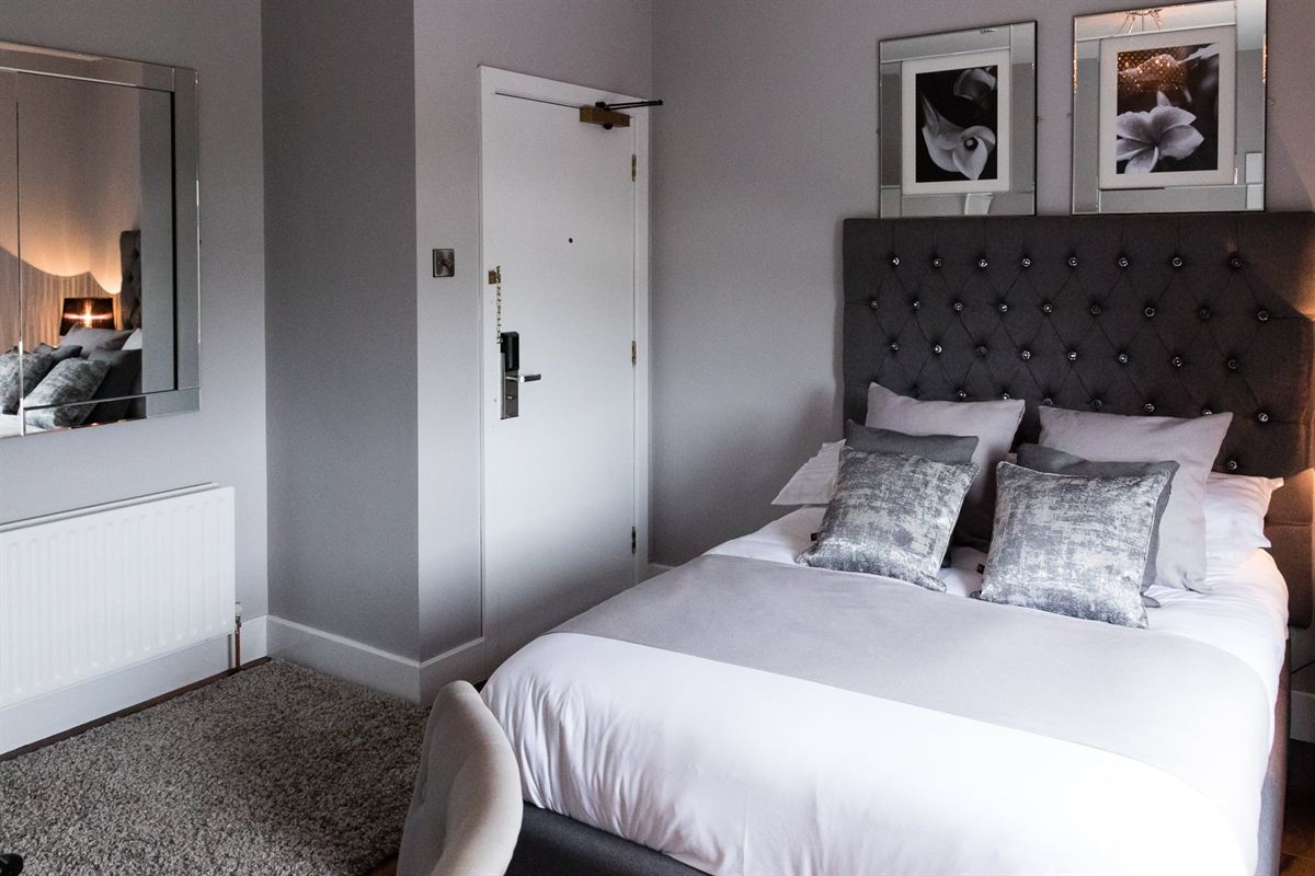 Double guest room with a tufted headboard and crushed-velvet cushions